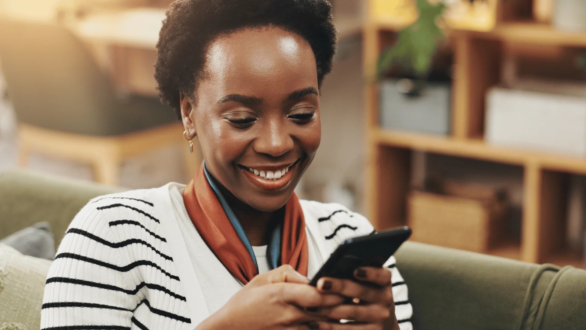 A young Nigerian woman smiling as she uses the Vtutopia mobile app on her phone